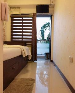 um quarto com uma cama e uma grande janela em Blue Paseo Grande Inn em Naga