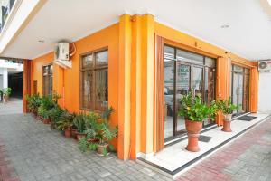 日惹的住宿－RedDoorz Plus @ Jalan Parangtritis 2，一座橘色的建筑,前面有盆栽植物