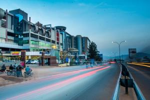 una calle de la ciudad con edificios y gente en bicicletas y coches en Freedom City Hotel Najjanankumbi Kamapala en Kampala