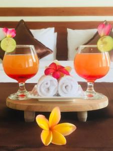 dos vasos de zumo de naranja y rosquillas en una bandeja en The Tinsi en Nusa Penida