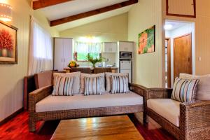 a living room with two wicker couches and a kitchen at Te Ava Beach Villas in Rarotonga