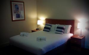 a hotel room with a bed and a lamp at Highlands Hotel in Mittagong