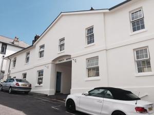 a white building with a car parked in front of it at Trinity Mews in Torquay