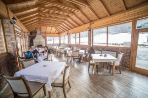a dining room with tables and chairs and windows at Vila "Volujak" in Tjentište