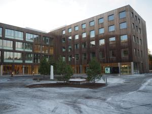 um grande edifício de tijolos com árvores em frente em Cathinka Guldbergs Hotell Gardermoen em Jessheim