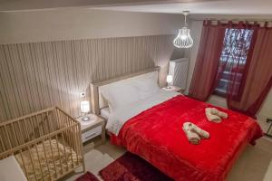 una camera da letto con un letto rosso con due scarpe sopra di Historic Luxury House in the Heart of Meteora a Kalabaka