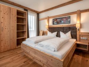 a bedroom with a large wooden bed with white pillows at Apartment Kristall in Finkenberg