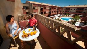 Ein Mann und eine Frau sitzen auf einem Balkon mit einem Obstteller in der Unterkunft Leo Punta Umbría - Adults Only in Punta Umbría