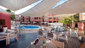 an outdoor patio with tables and chairs and a pool at Leo Punta Umbría - Adults Only in Punta Umbría
