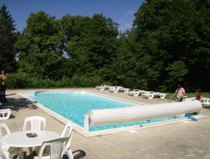 a swimming pool with white chairs and tables and chairs at Le Chateau de Prauthoy in Prauthoy