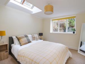 a bedroom with a white bed and a window at Rosemount Cottage in Helensburgh