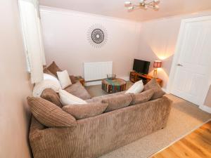 uma sala de estar com um sofá castanho e uma televisão em Carrington Cottage em Lincoln