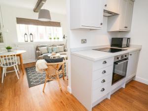 a kitchen and living room with white cabinets and a table at 3 Poole End in Clitheroe
