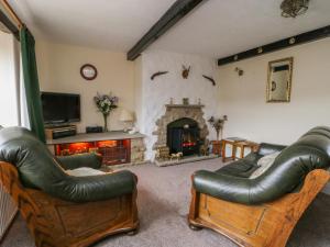 a living room with leather furniture and a fireplace at Acorn Cottage in Bradford