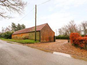 an old brick building on the side of a road at Honey Buzzard Barn in Fakenham