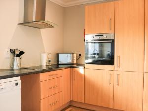 a kitchen with wooden cabinets and a microwave at Taigh Chailean in Lochs