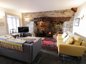 a living room with two couches and a stone fireplace at Goronwy Cottage in Barmouth