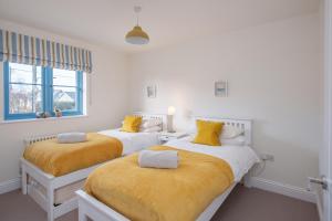 zwei Betten in einem weißen Zimmer mit gelben Kissen in der Unterkunft Crab Cottage in Bembridge + 43 Fotos