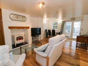 een woonkamer met 2 witte stoelen en een open haard bij Preswylfa Apartment in Caernarfon