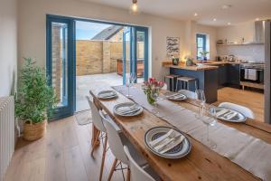 a dining room with a wooden table and a kitchen at Crab Cottage in Bembridge