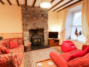 a living room with a stone fireplace and red furniture at Edrydd in Harlech