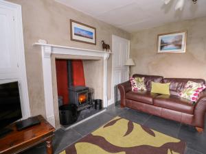 a living room with a leather couch and a fireplace at Llwyncadfor Farm in Llangynllo