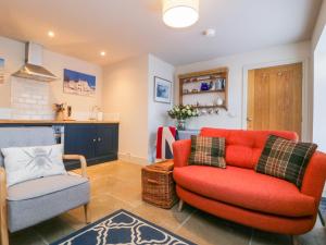 a living room with a red couch and a chair at Wallerthwaite Barn Cottage in Harrogate