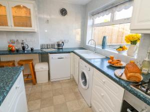 a white kitchen with a sink and a dishwasher at Sea Roke in Filey
