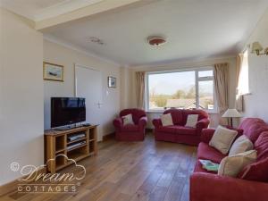 a living room with two red couches and a tv at Hillview Bungalow in Burton Bradstock