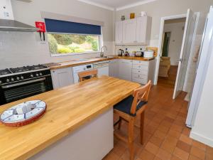 une cuisine avec des armoires blanches et un comptoir en bois dans l'établissement Ashdown House, à Saundersfoot