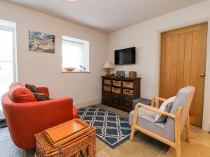 a living room with two chairs and a tv at Wallerthwaite Barn Cottage in Harrogate