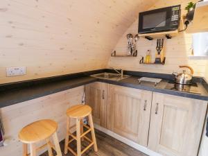 a kitchen in a tiny house with a sink and two stools at Gelert Pod in Tremeirchion