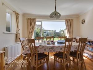 - une salle à manger avec une table et des chaises dans l'établissement Hillview Bungalow, à Burton Bradstock