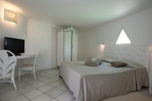 a bedroom with a bed and a desk and a television at Hotel Mare Pineta in Santa Margherita di Pula