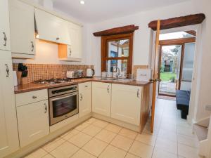 a kitchen with white cabinets and a stove top oven at 3 School View in Ulverston