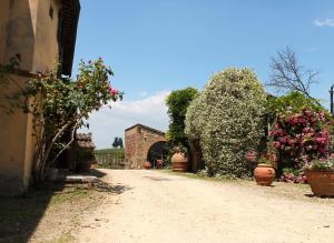 a dirt road with flowering plants and a building at Case Coloniche Berni in Impruneta