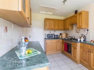 a kitchen with wooden cabinets and a counter top at Hillview Bungalow in Burton Bradstock +19 photos