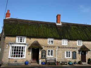 an old brick building with a grass roof at Hillview Bungalow in Burton Bradstock