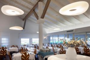 un restaurante con mesas y sillas blancas y un jarrón de flores en Hotel Mare Pineta, en Santa Margherita di Pula