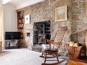 a stone fireplace with a rocking chair in a living room at Lowena in Penzance