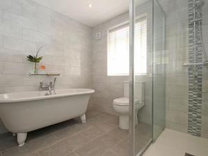 a bathroom with a tub and a toilet and a glass shower at Seagrass in Newquay