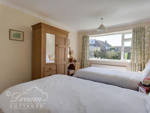 a bedroom with two beds and a window at Hillview Bungalow in Burton Bradstock
