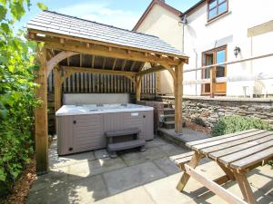 a barbecue under a wooden pergola next to a bench at Lilly Cottage in Lydney