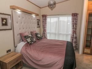 ein Schlafzimmer mit einem großen Bett mit rosa Bettwäsche und einem Fenster in der Unterkunft Avonal Lodge 24 in Perth