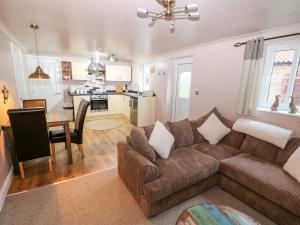 a living room with a brown couch and a kitchen at Carrington Cottage in Lincoln