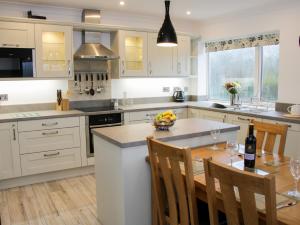 a kitchen with white cabinets and a table with a bowl of fruit at Rock View Cottage in Llanymynech