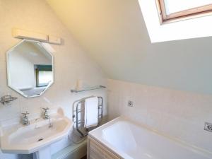uma casa de banho com um lavatório, uma banheira e um espelho. em Slade Tops em Ashbourne