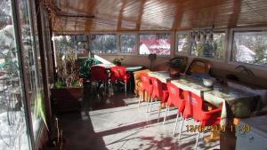 a room with red chairs and a table and windows at Vila Marcela in Buşteni