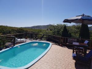 a swimming pool with a chair and an umbrella at Residencial Emery Village in Garopaba