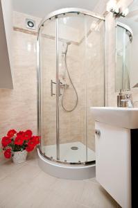 a bathroom with a shower and a sink and red flowers at Domki Wioska Rybacka in Hel +43 photos